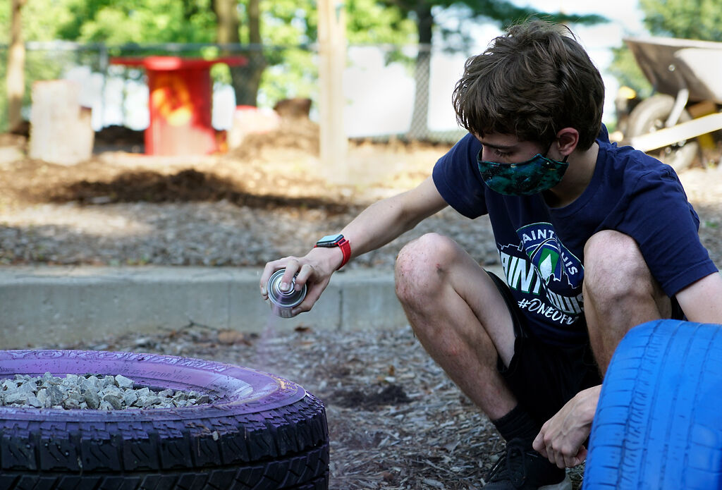 Denniel Webb, 15, paints tires on Thursday at Derby Ridge Elementary